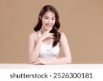 Pretty Asian woman model perfect clear fresh skin smile on isolated beige background. Portrait female beauty blogger make up artist in studio. Skincare, plastic surgery, spa concept.