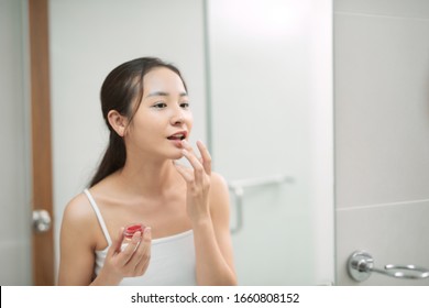 Pretty Asian Woman Putting Balm On Lips.