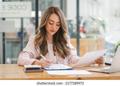 Pretty Asian woman sitting in the office, calculator, working on data, charts and documents on the table in business workspace. - Shutterstock ID 2177289973