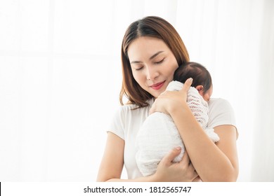 Pretty Asian Woman Smile And Holding A Newborn Baby In Her Arms. Happy Family. Asia Mother Lifting Her Adorable Infant Baby On White. Love People Concept