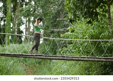 Pretty Asian woman walking at the suspension bridge over the stream in the forest which is a tourist attraction happily. - Powered by Shutterstock