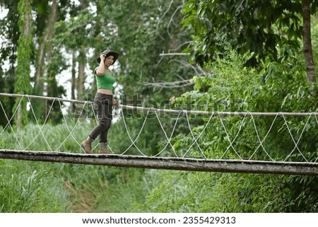 Pretty Asian woman walking at the suspension bridge over the stream in the forest which is a tourist attraction happily. Stock photo © 