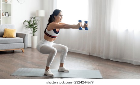 Pretty athletic motivated young brunette woman standing on yoga mat at home, training with weights, looking at copy space, wearing tight white sportswear. Home workouts for women concept, panorama - Powered by Shutterstock