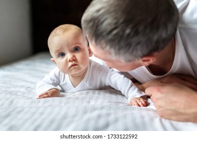 Pretty baby with dad on a white sheet on the bed. Cute infant child with father. Can be used in journal. Newborn baby and dad, a newborn baby in her husband's arms. Father with son or daugher - Shutterstock ID 1733122592
