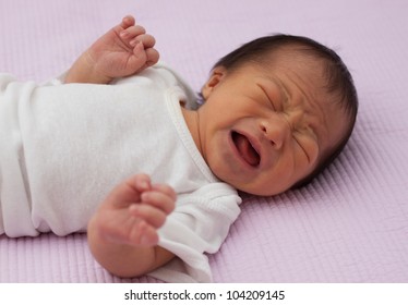 Pretty Baby Newborn Asian infant girl upset and crying with wrinkles in face