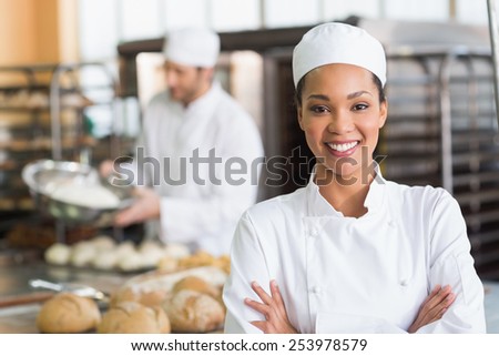Pretty baker smiling at camera in the kitchen of the bakery