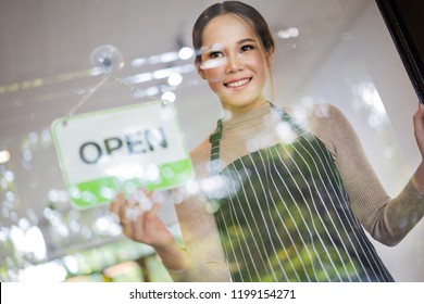 Pretty barista of the cafe with Open sign - Powered by Shutterstock