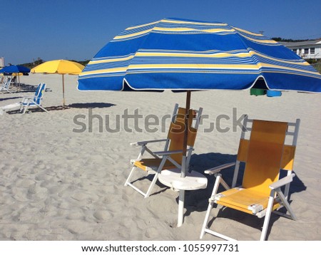 Pretty beach chairs and umbrella at the seashore.