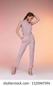 Pretty beautiful sexy elegance woman fashion model glamour pose wear pink color trousers silk blouse suit clothes party summer collection makeup office hair style brunette success accessory jewelry.
