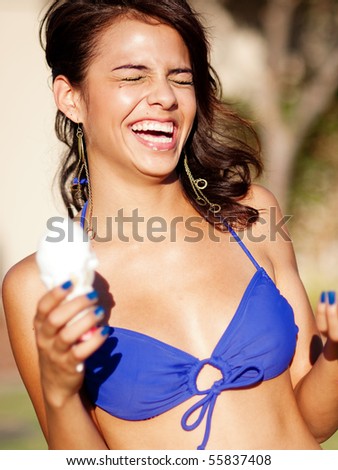 Pretty beautiful young woman in bikini eating ice cream laughing and having fun