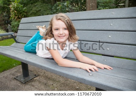 pretty beauty child girl lying on wood bench in garden park