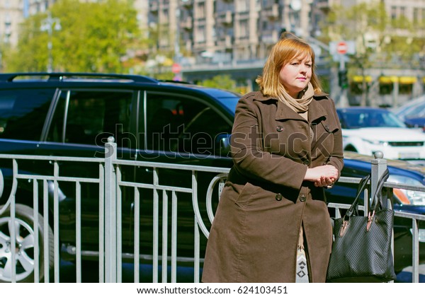 Pretty big woman of size\
plus size walks in the city, enjoys a sunny day and good weather in\
the rhythm of a big city life, cars and roads finds happiness in\
every day