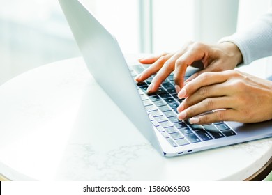 Pretty, black, female hands with pink manicured nails type away on an unbranded laptop, perhaps online shopping. Photo includes ample copy space. - Powered by Shutterstock