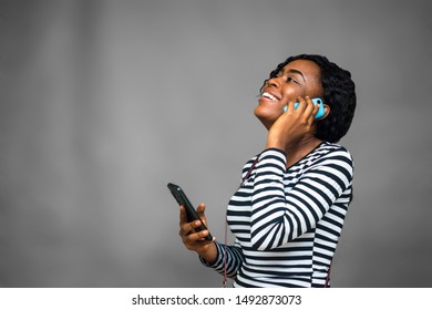 Pretty Black Girl Smiling And Making A Phone Call, Holding Another Phone In Her Other Hand