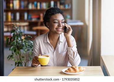 Pretty black girl talking on mobile phone during her lunch at coffee shop