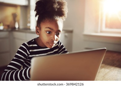 Pretty Black Teen Girl Watching A Movie On Her Laptop Computer Seriously At Home.
