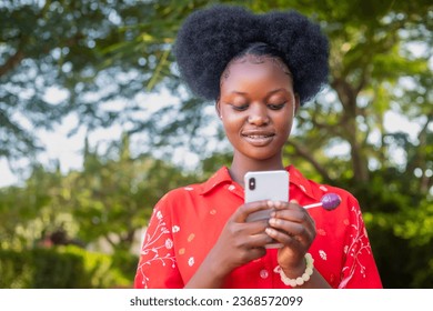pretty black woman look very excited and rejoices while looking at her phone - Shutterstock ID 2368572099