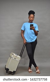 Pretty Black Woman Using Her Mobile Phone, Holding Her Traveling Box, Looking Casual, Booking Her Travel Online