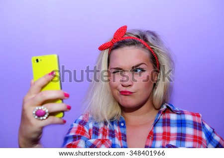 Pretty blog girl with blue eyes wink to smartphone durin making selfie. Happy smile posing in retro fashion style.