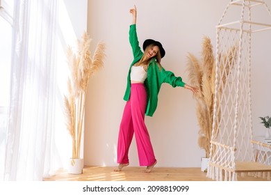 Pretty blond girl dancing and having fun in studio on white background and pampass decor. Wearing trendy bright stylish outfit, hat. Summer mood. - Shutterstock ID 2098819099