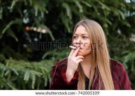 Hübsches blondes Mädchen mit langen Haaren, das raucht.