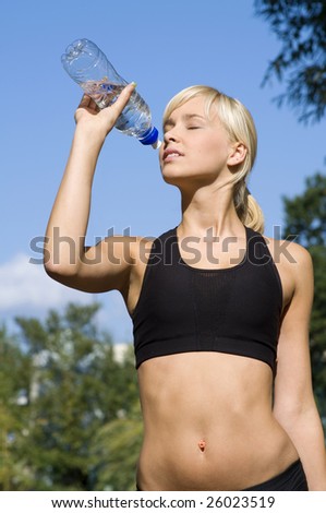 pretty blond girl in sport wear drinking from a sport bottle outdoor