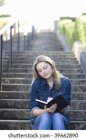 Pretty Blond Teen Girl Sitting On A Stairway Writing In Journal