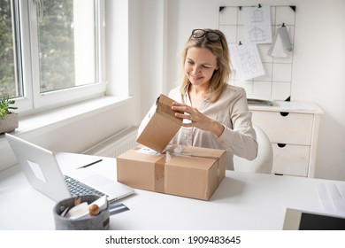 pretty blonde business woman sitting in her office and just got some packages, gifts, delivery from online order and is happy