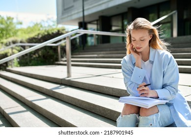 Pretty blonde girl college student holding notebook sitting on stairs outside campus writing checklist essay for university study course, looking for inspiration, thinking of new creative ideas plan - Powered by Shutterstock