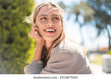 Pretty blonde Uruguayan woman with glasses at outdoors With happy expression - Shutterstock ID 2313877035