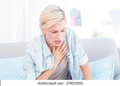 Pretty blonde woman having breath difficulties in the living room - Shutterstock ID 274015055