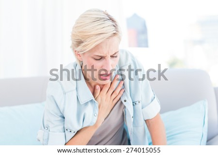 Pretty blonde woman having breath difficulties in the living room