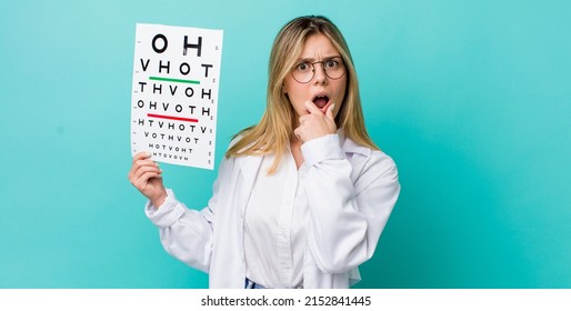 pretty blonde woman with mouth and eyes wide open and hand on chin. optical vision test concept