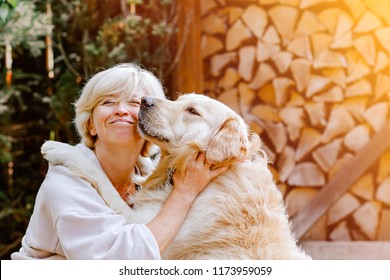 Pretty blonde woman playing with her dog golden retriever