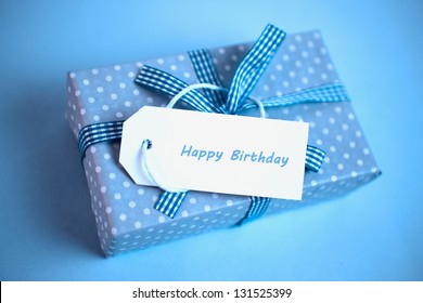 Pretty Blue Gift With A Happy Birthday Card On A Blue Background Close Up