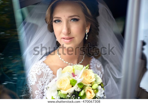 Pretty bride\
with tender rose lips sits in the\
car