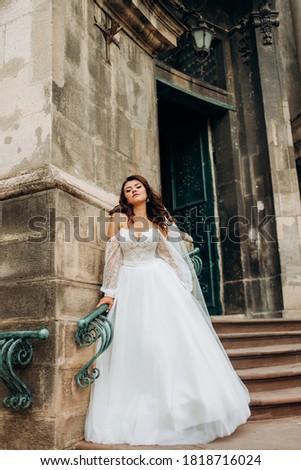 Pretty bride in a vintage dress posing near an old building.