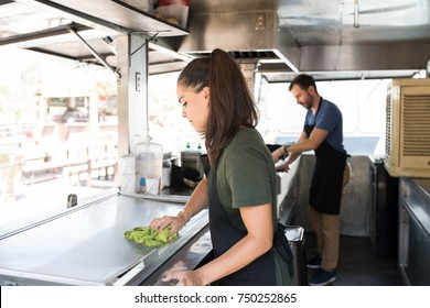 Pretty brunette cleaning her food truck and getting ready to cook some food for her customers - Powered by Shutterstock