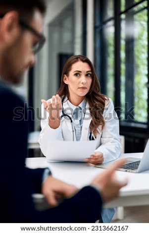 A pretty brunette female doctor talking with a worried male patient with glasses on, across the ambulance table.