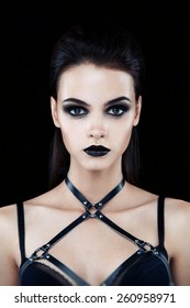 Pretty brunette female fashion model posing in studio with dark gothic make up