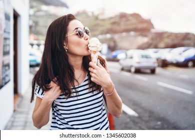 Pretty brunette girl eating ice cream and walking outdoor on the street