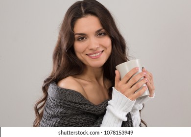 Pretty brunette model in gray cardigan holding cup of coffee. Isolated on white background. Mid age woman over 35 years old beauty concept.