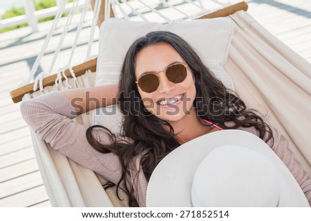 Pretty brunette relaxing on a hammock in patio