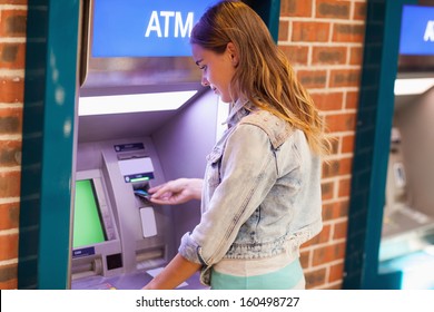 Pretty brunette student withdrawing cash at an ATM