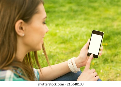 Pretty brunette teenage girl with smartphone outdoors in park. Closeup of female hands and smart phone with isolated white screen. Mock-up concept.