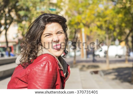 Pretty brunette woman with red leather jacket 
sticking out tongue