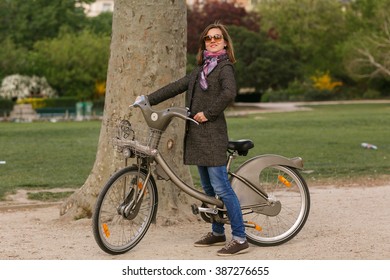 Pretty brunette young woman riding a bicycle in Paris - Shutterstock ID 387276655
