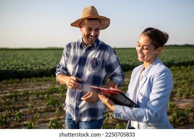 Pretty business woman and handsome farmer signing documents on field in summer time - Shutterstock ID 2250705833