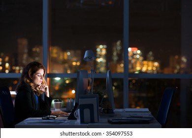 Pretty Business Woman Working Alone In Dark Office