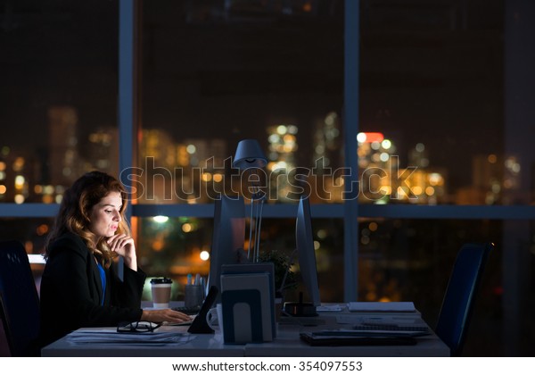 Pretty
business woman working alone in dark
office